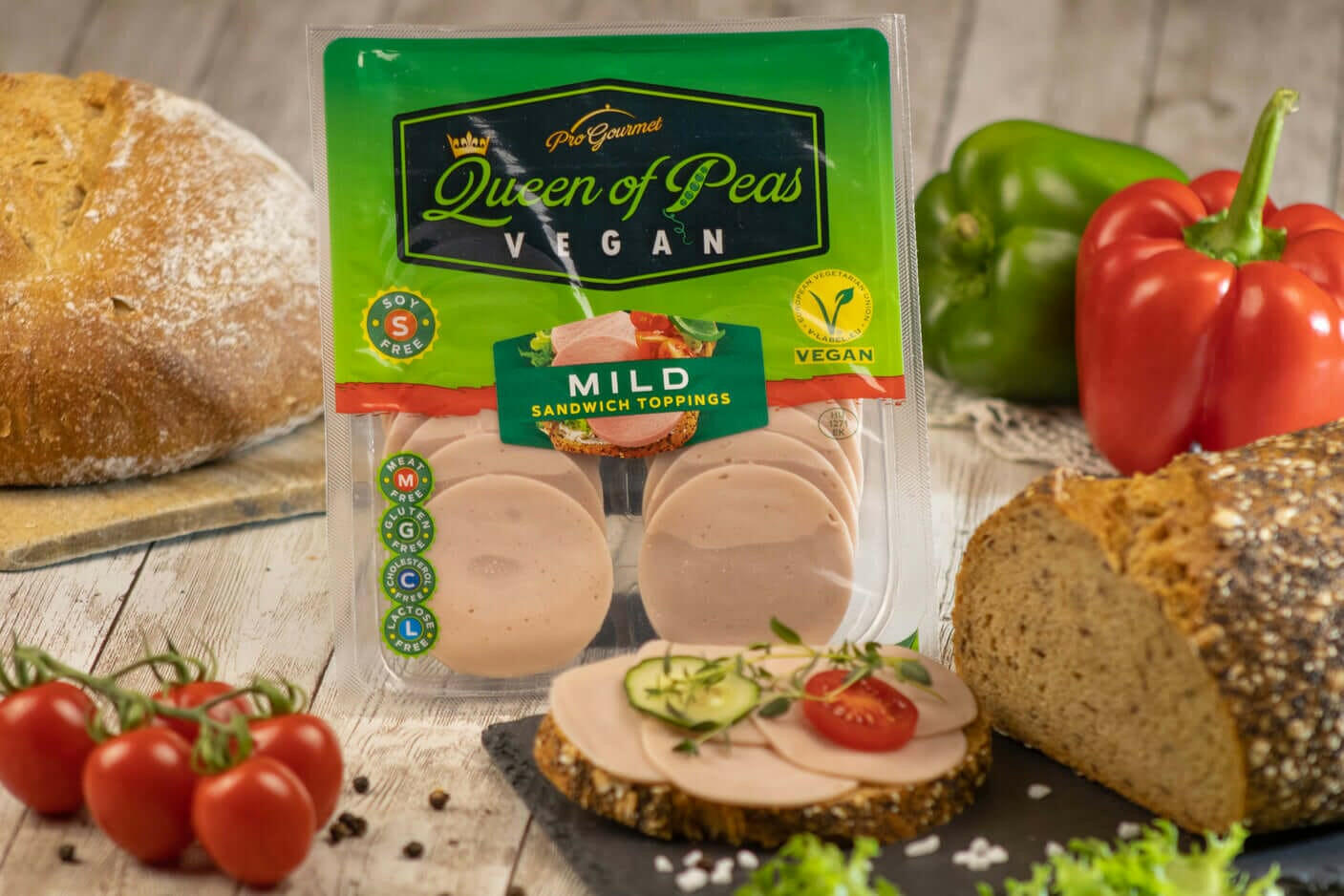 Plant-based vegan sliced mild sandwich toppings, allergen-free and healthy, displayed with fresh bread, tomatoes, and peppers.